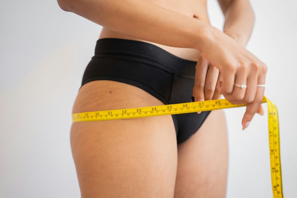 A woman is measuring her booty during her weight loss journey A woman measuring her booty
