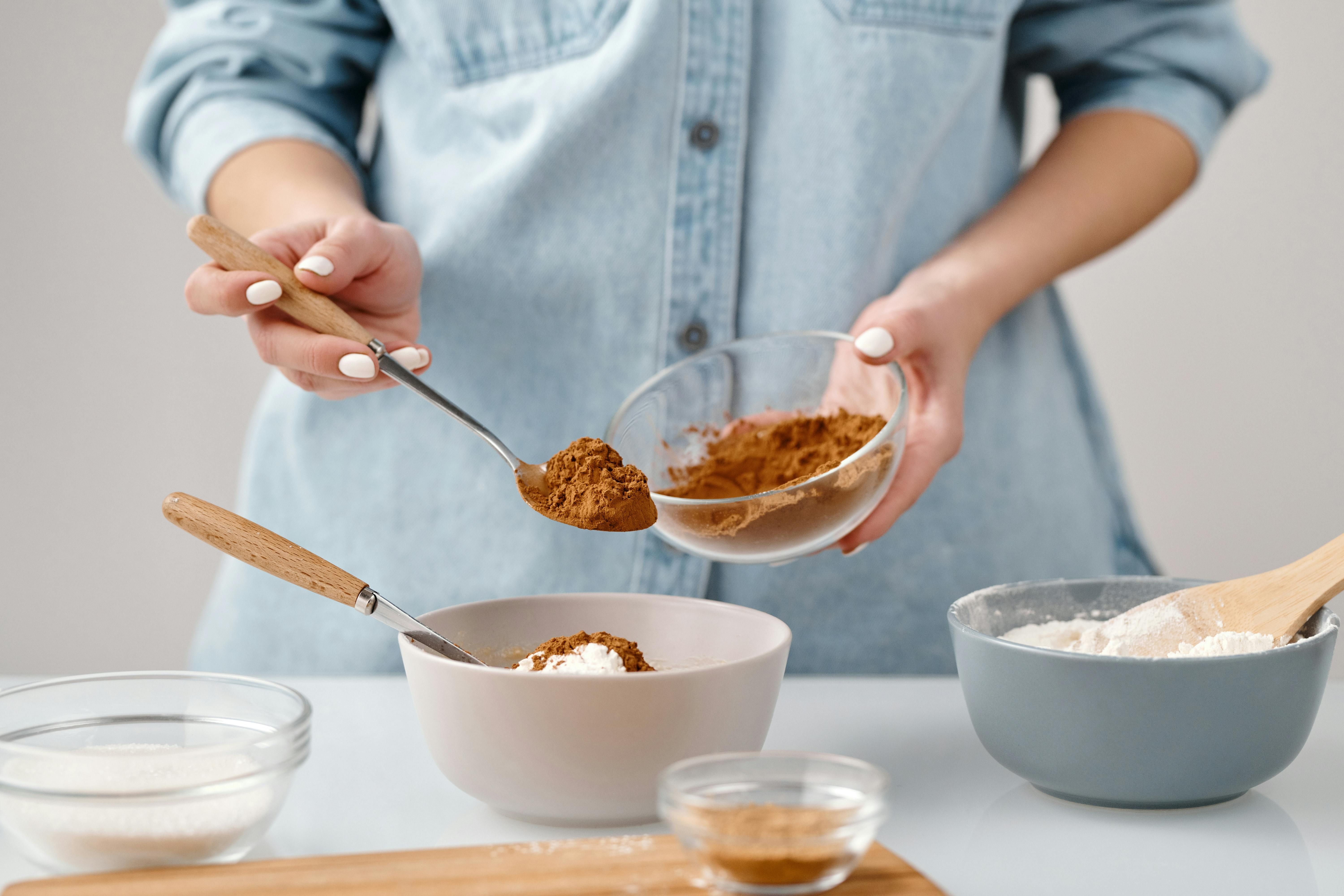 Cooking with Cinnamon - A Woman Adds Spice to Her Healthy Recipe. Woman sprinkling cinnamon into a dish while cooking, enhancing flavor naturally.