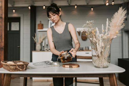 A woman sipping a cup of steaming black tea while intermittent fasting, highlighting the balance between a comforting morning ritual and fasting objectives