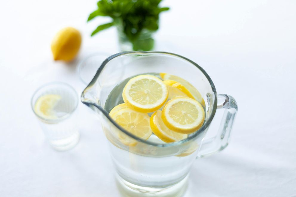 The 2024 Guide to Infused Water: Creative Recipes for Healthy Hydration A woman preparing a pitcher of infused water with fresh fruit and herbs, making hydration both healthy and enjoyable.