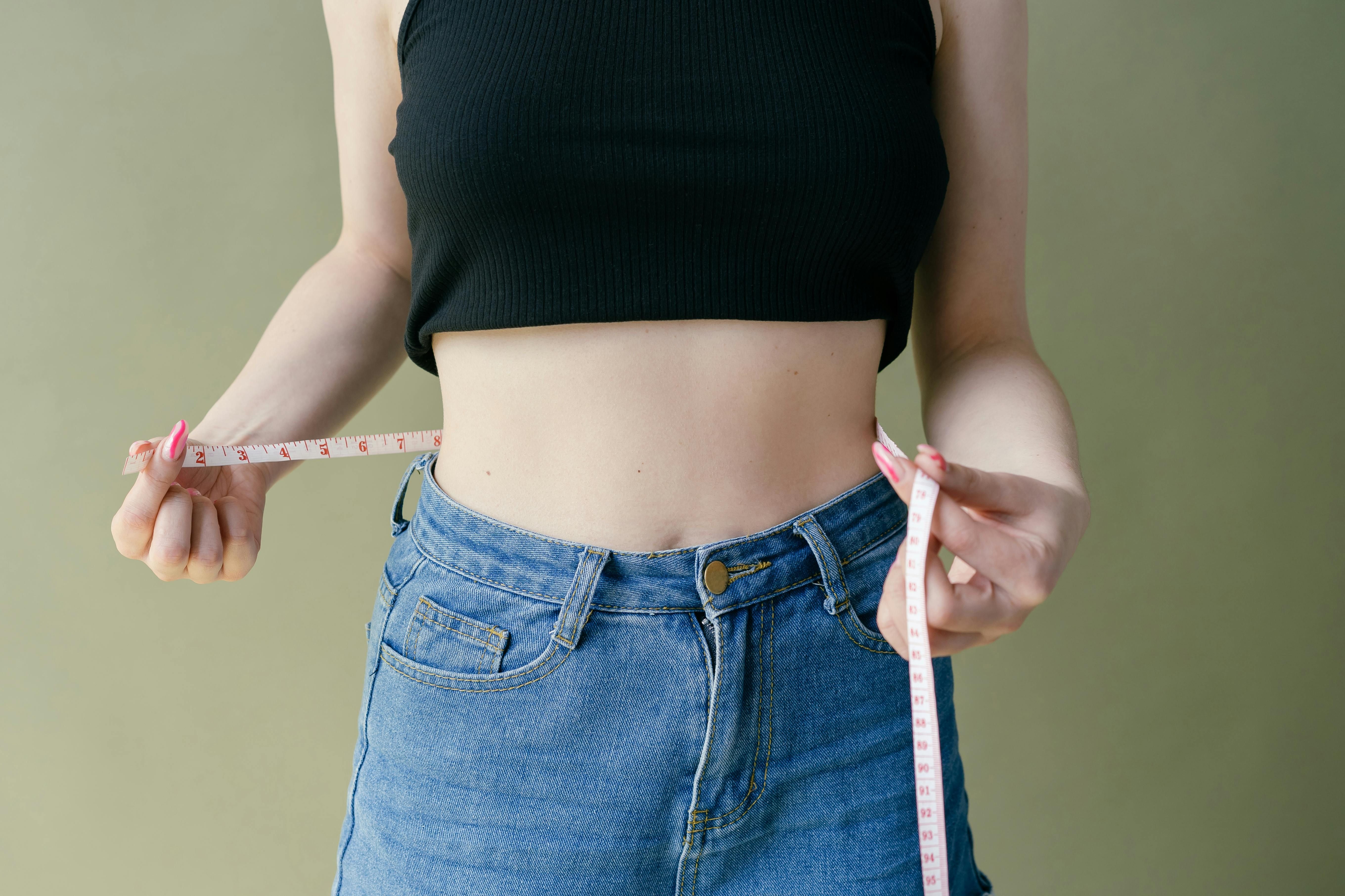 The Role of Weight Management in Alleviating Sleep Apnea Symptoms Woman measuring her waistline, highlighting the link between weight loss and sleep apnea improvement