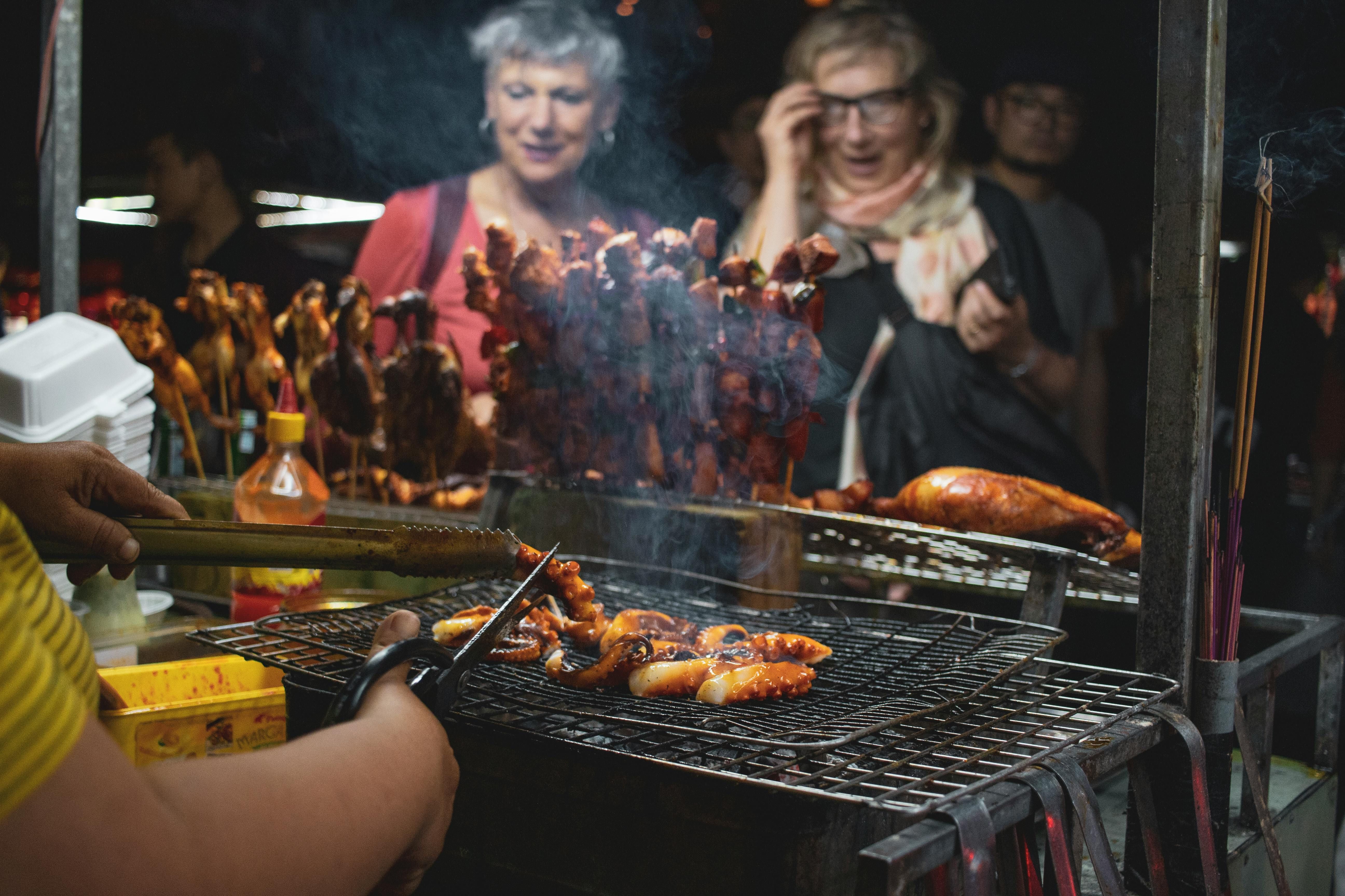 Women Exploring Exotic Grilled Meats: Enhancing the Carnivore Diet with Unique Flavors Women enjoying exotic grilled meats and seafood, embracing diverse flavors on the carnivore diet.